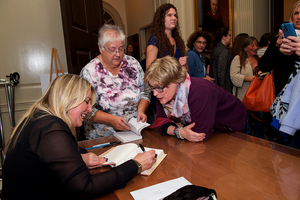 Esther Gray helps author and guest lecturer Cheryl Strayed sign books after her talk. Esther Gray is retiring after this semester.