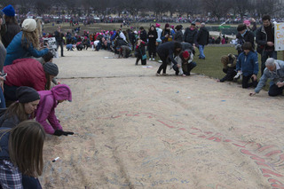 People sign their names and write messages on a scroll titled 